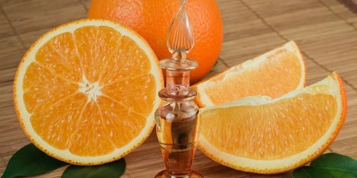 Апельсиновое эфирное масло в флаконе и нарезанный апельсин