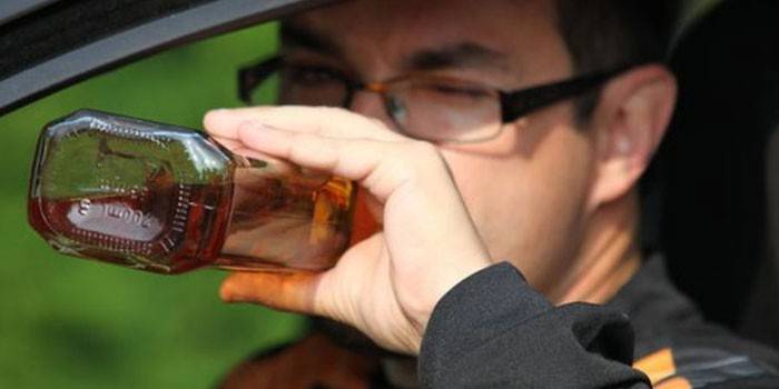 Мужчина в машине пьет алкоголь из бутылки