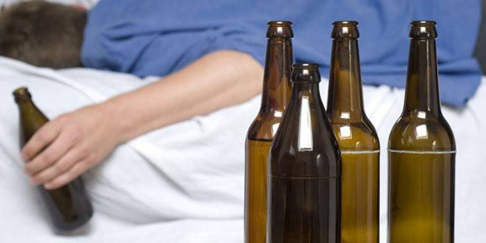 Мужчина лежит на кровати с бутылкой в руке