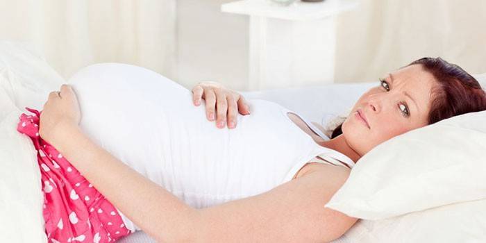 Беременная женщина лежит в постели