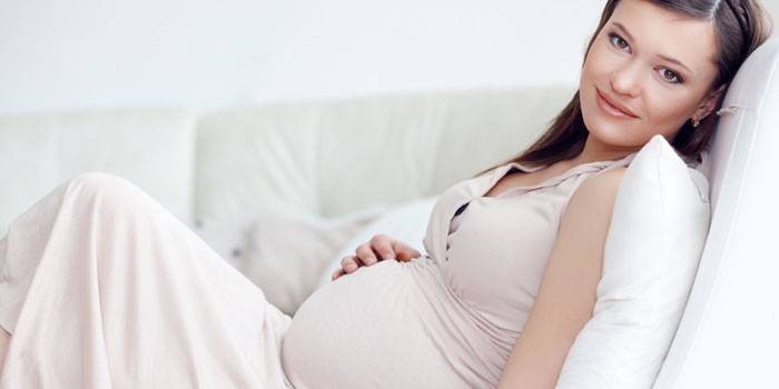 Беременная девушка сидит на диване