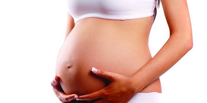 Беременная женщина обнимает живот