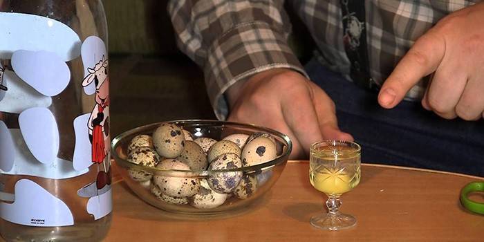 Мужчина, перепелиные яйца в стеклянной миске и сырое яйцо в рюмке
