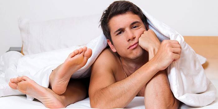 Мужчина в постели под одеялом и женские ступни
