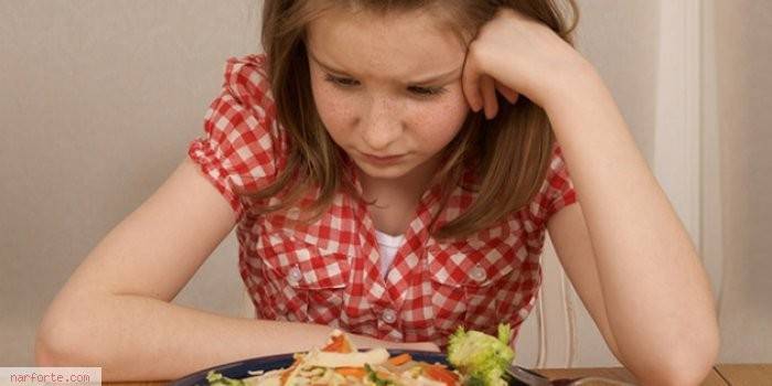 Девочка смотрит на тарелку с едой