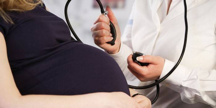 Врач измеряет давление беременной женщине
