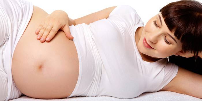 Беременная женщина гладит живот