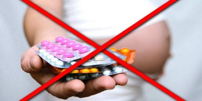 Перечеркнутое изображение беременной с таблетками в руке