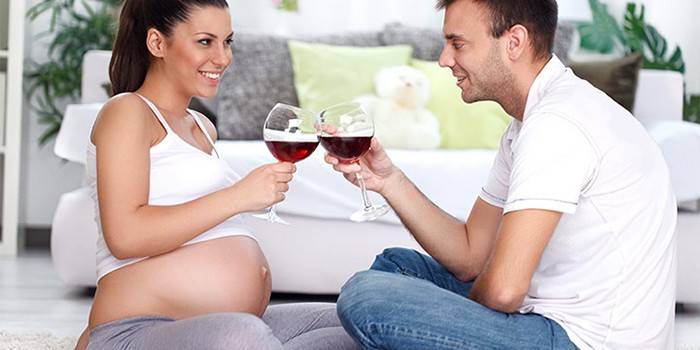 Беременная женщина пьет вино в компании мужчины