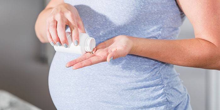 Беременная женщина с таблеткой в руке