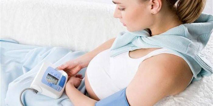 Беременная женщина измеряет себе давление