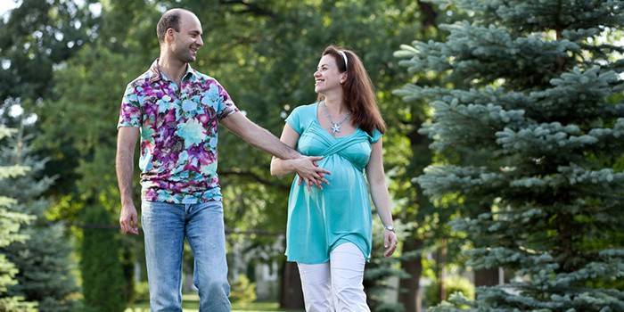 Беременная женщина с мужем на прогулке в парке