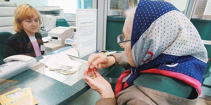 Пожилая женщина получает пенсию в банке