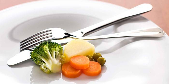 Тарелка с небольшой порцией овощей и столовые приборы