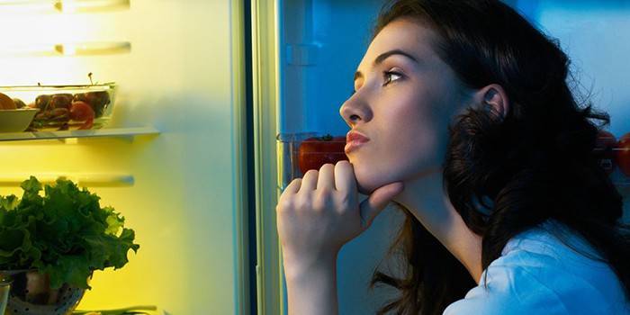 Задумчивая девушка возле холодильника