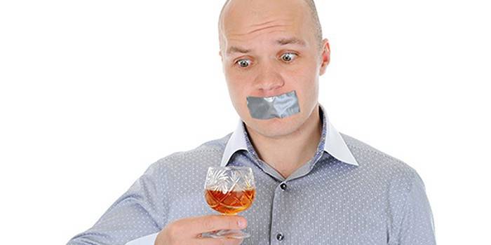 Мужчина с заклеенным ртом и бокалом с алкоголем в руке