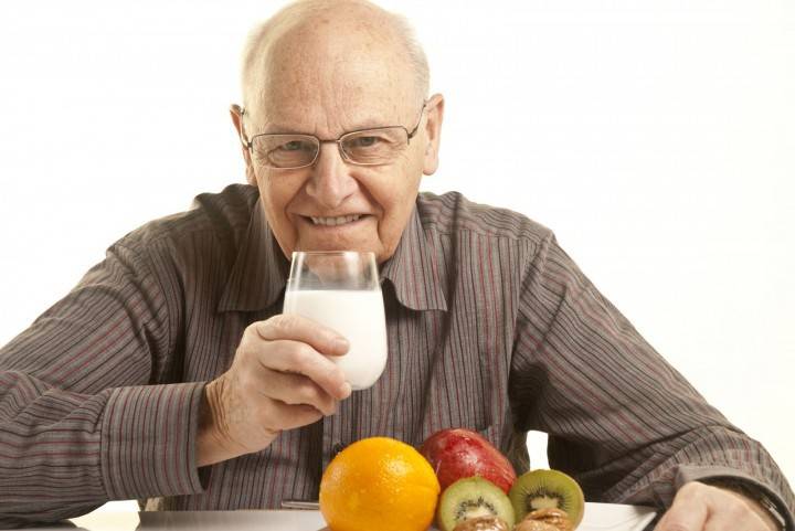 Пожилой мужчина со стаканом кефира и фрукты