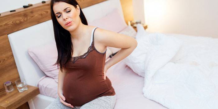 Беременная женщина сидит на кровати