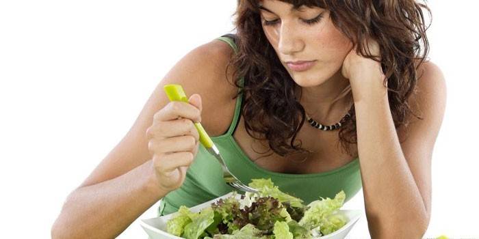 Женщина смотрит на тарелку с салатом