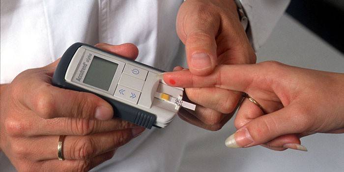 Врач измеряет уровень сахара в крови пациентки глюкометром