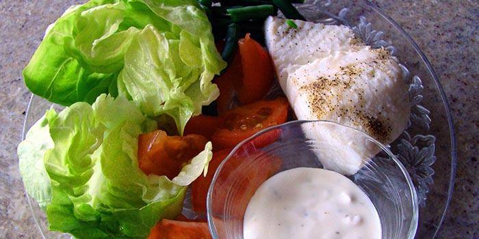 Куриная грудка, овощной салат и соус на тарелке