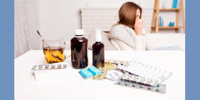 Простывшая женщина и лекарства на столе