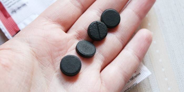 Таблетки активированного угля на ладони
