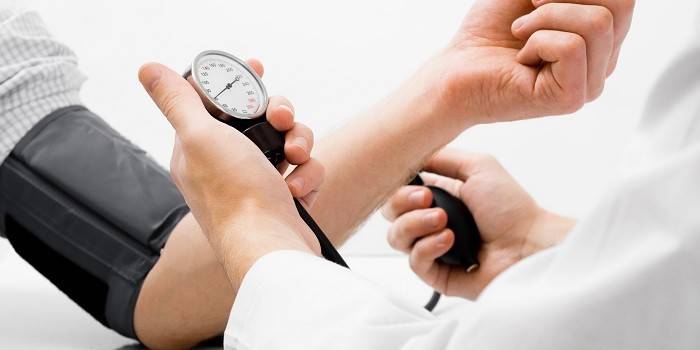 Медик измеряет артериальное давление человеку