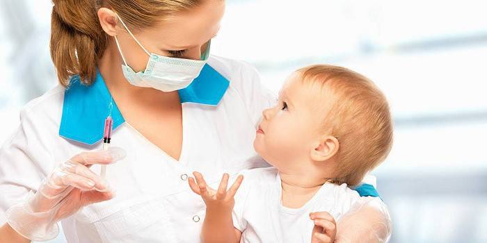 Медик держит на руках ребенка и шприц с препаратом