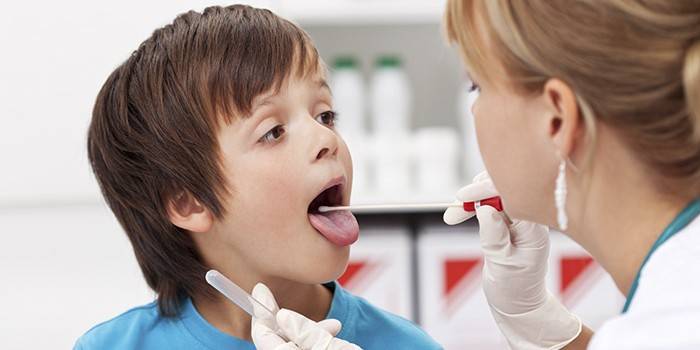 Медик берет мазок из горла у ребенка