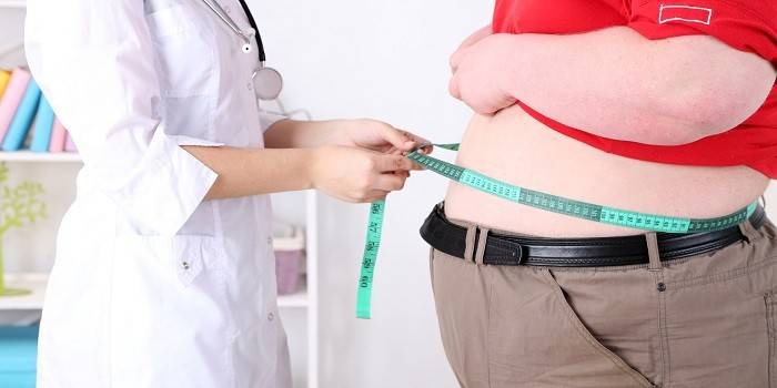 Врач измеряет объем талии человека страдающего ожирением