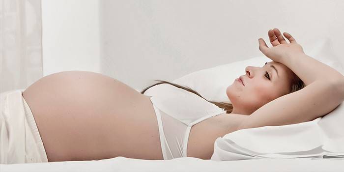 Беременная женщина лежит в кровати