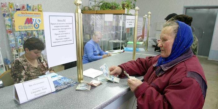 Женщина получает пенсию в почтовом отделении