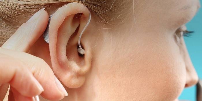 Заушный слуховой аппарат на ухе у девушки
