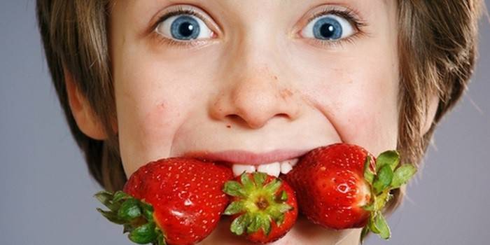 Мальчик с ягодами клубники во рту