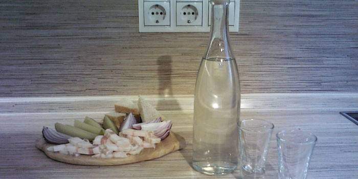 Самогон в бутылке, две стопки и закуска