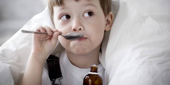 Ребенок пьет лекарство из ложки