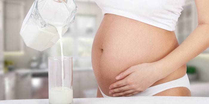 Беременная женщина наливает ряженку в стакан